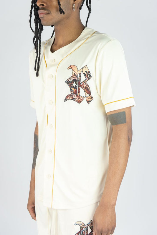 Person wearing a white baseball jersey with a logo on a plain background