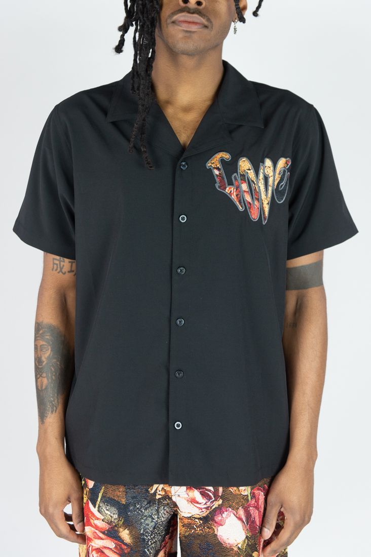 Person wearing a black button-up shirt with colorful text design on a white background