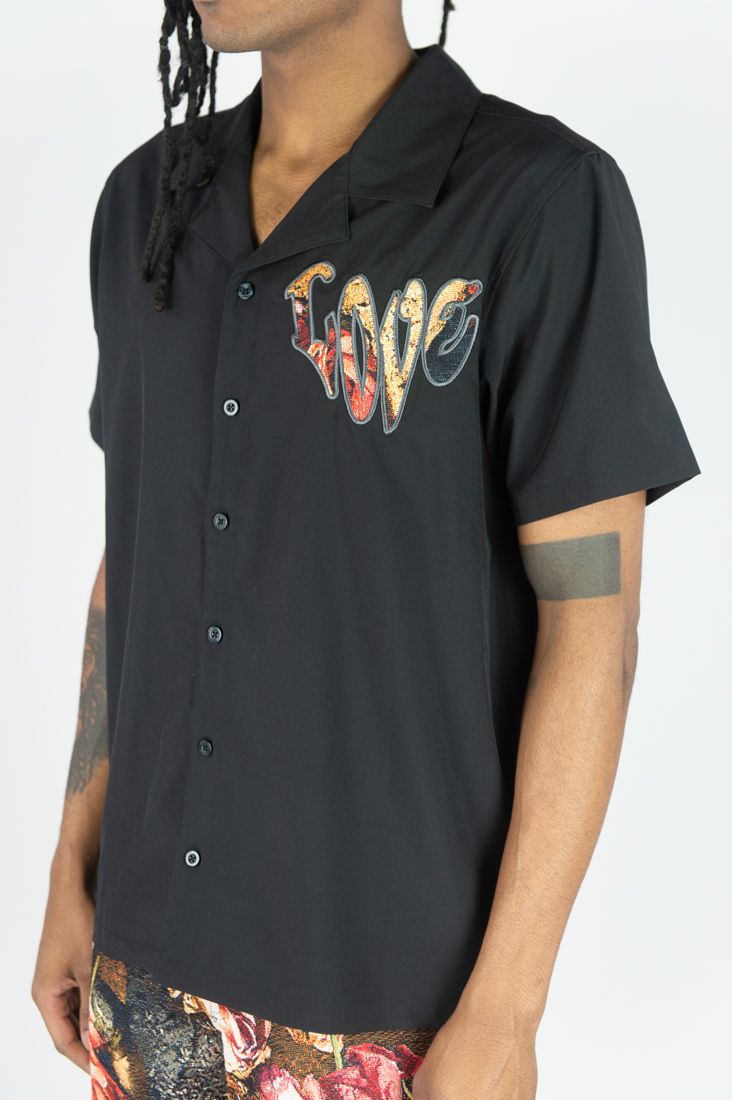 Person wearing a black sleeveless shirt with 'LOVE' printed on it against a white background