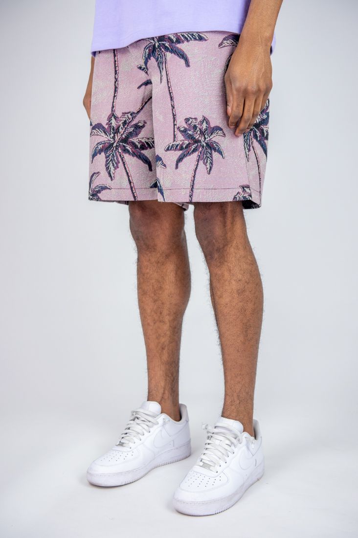Person wearing a pink floral skirt with white sneakers on a white background