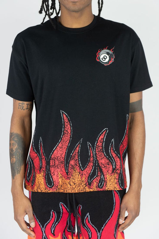 Person wearing a black t-shirt with flame design and matching pants on a white background