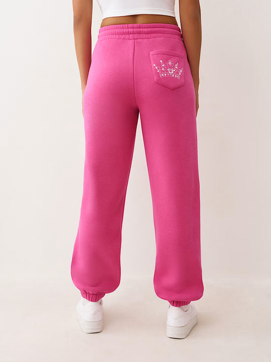 Person wearing bright pink sweatpants with a small logo on the back pocket against a light background