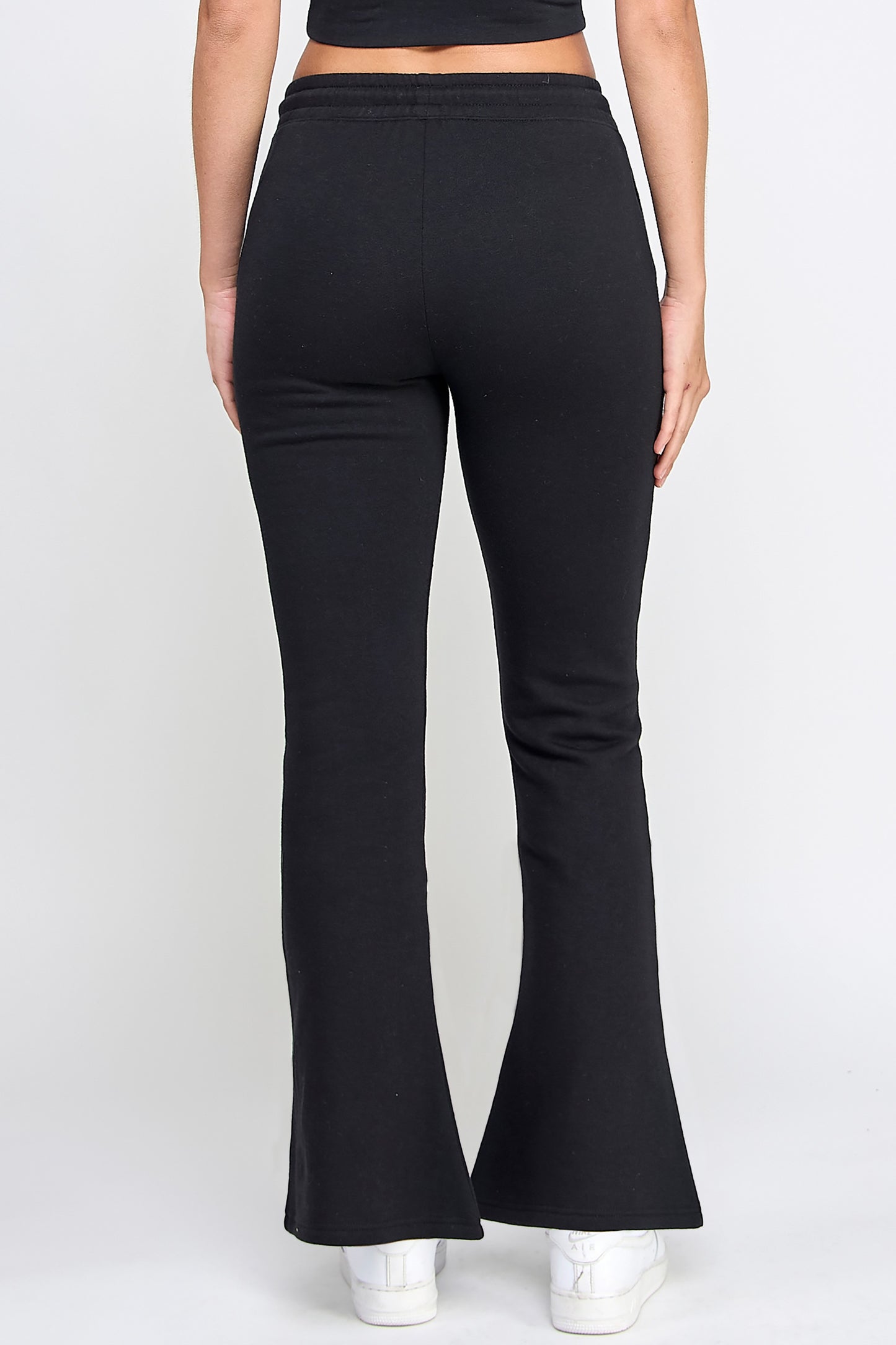 Black flared pants worn by a person on a white background