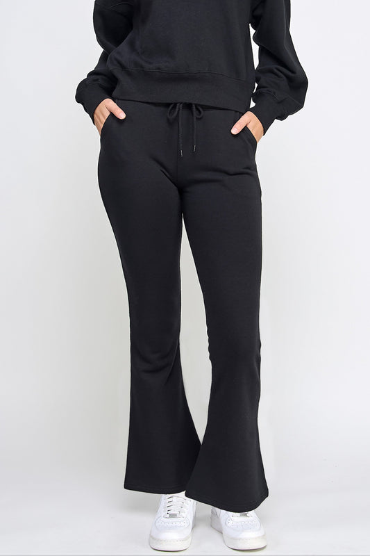 Person wearing black flared pants and a matching top on a white background