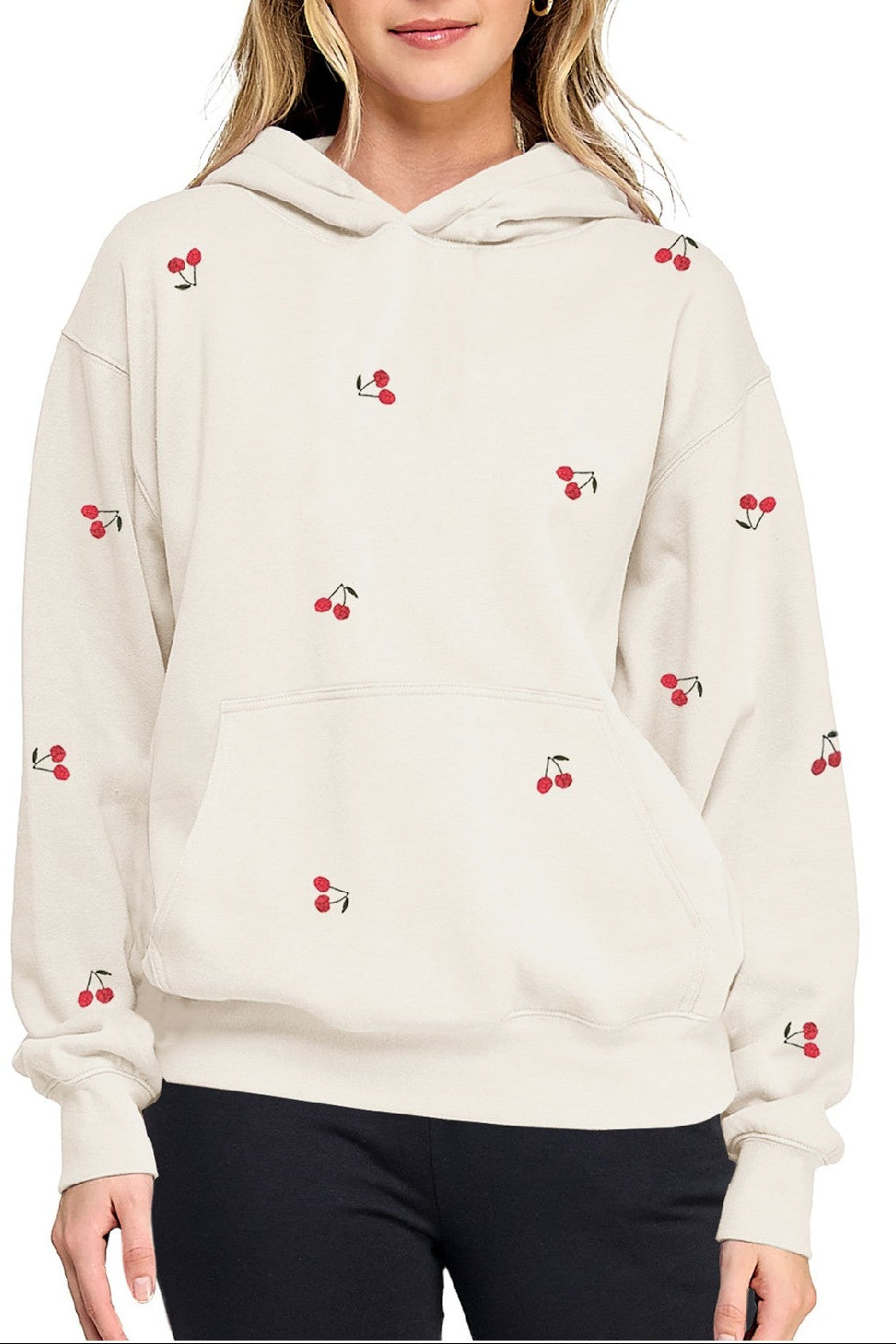 Woman wearing a cream hoodie with cherry patterns on a white background