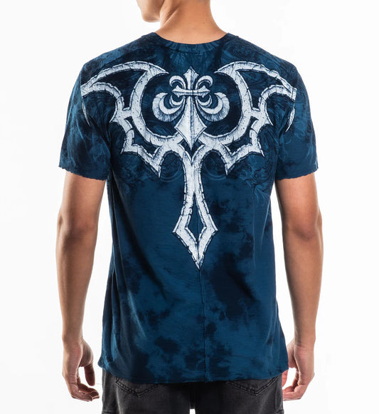 Blue t-shirt with a white intricate design on the back, worn by a person.