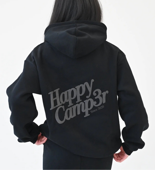 Person wearing a black hoodie with 'Happy Camp3r' text on the back against a white background