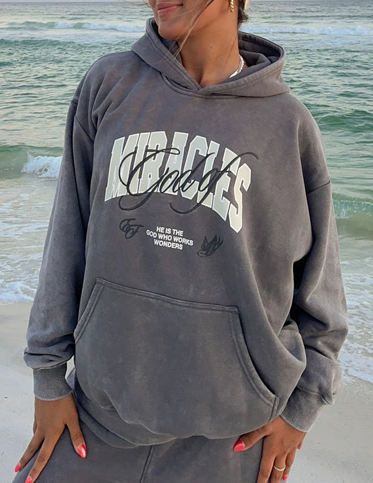 Person wearing a gray hoodie with text on a beach