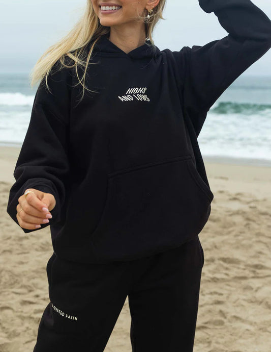 Person wearing a black hoodie and pants on a beach