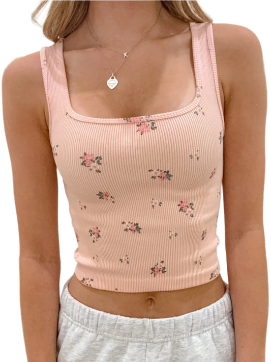 Person wearing a pink floral tank top and gray sweatpants against a white background