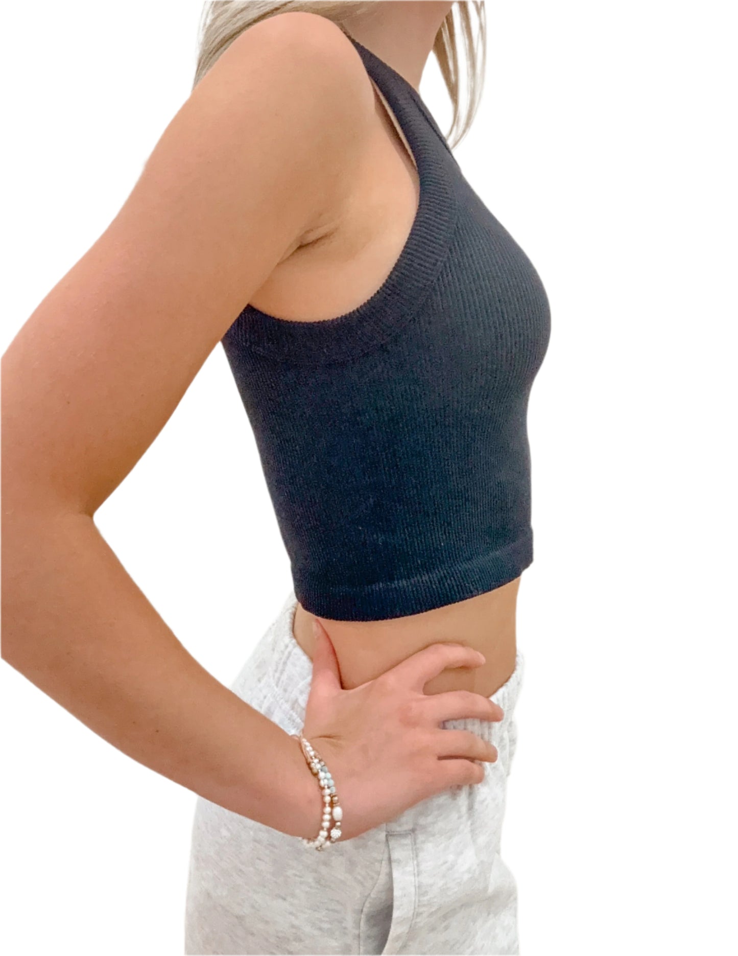 Person wearing a dark blue knitted crop top and light gray pants against a white background