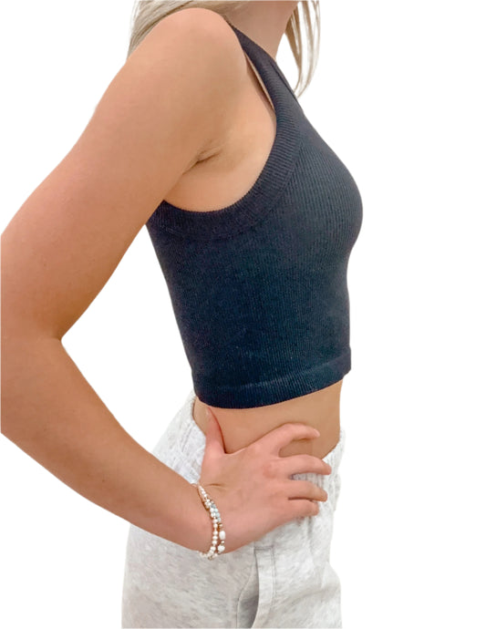 Person wearing a dark blue knitted crop top and light gray pants against a white background