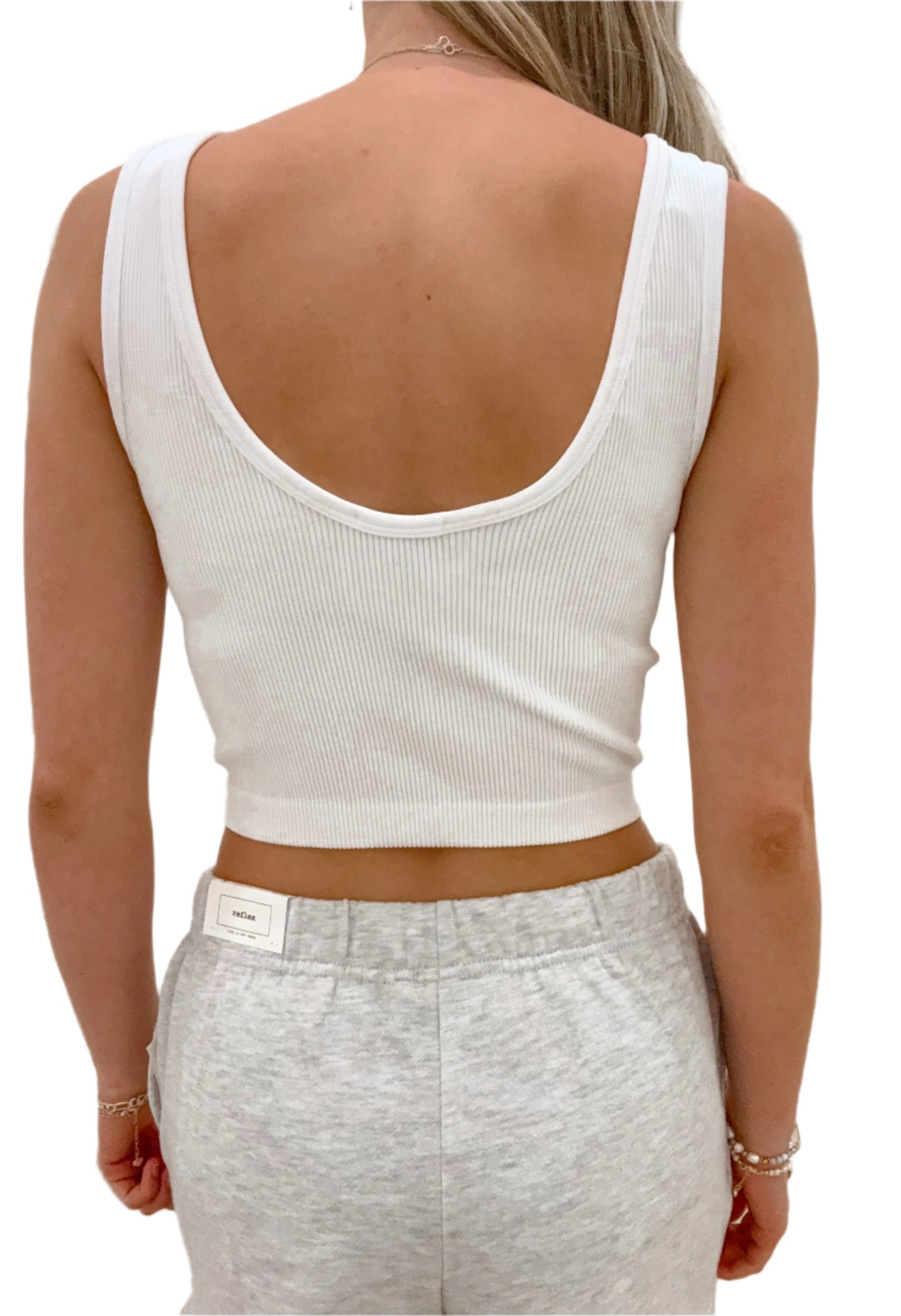 Person wearing a white tank top and gray pants with a blurred background