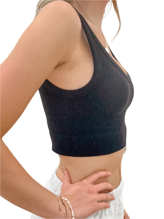 Person wearing a black crop top and white pants against a neutral background