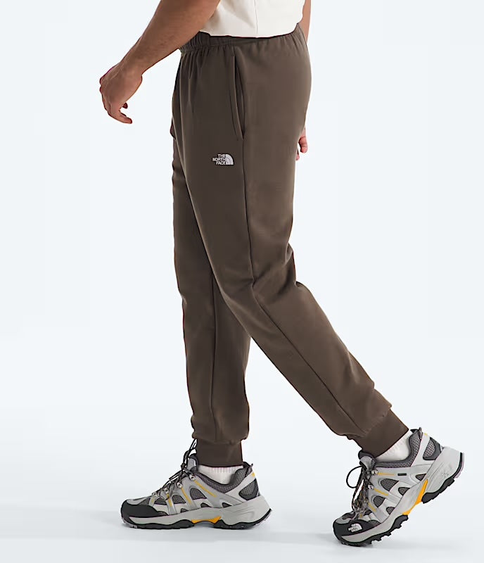 Person wearing brown The North Face pants with hiking shoes on a white background