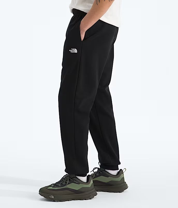 Person wearing black pants with a brand logo on a white background