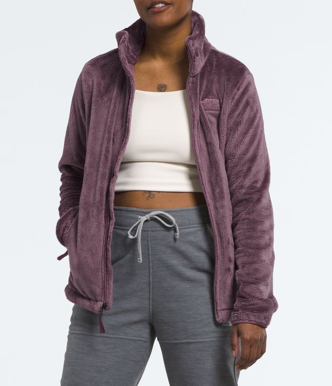 Person wearing a purple jacket, white top, gray pants, and white sneakers on a light gray background