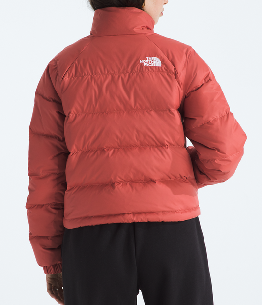 Person wearing a red puffer jacket with The North Face logo on a white background