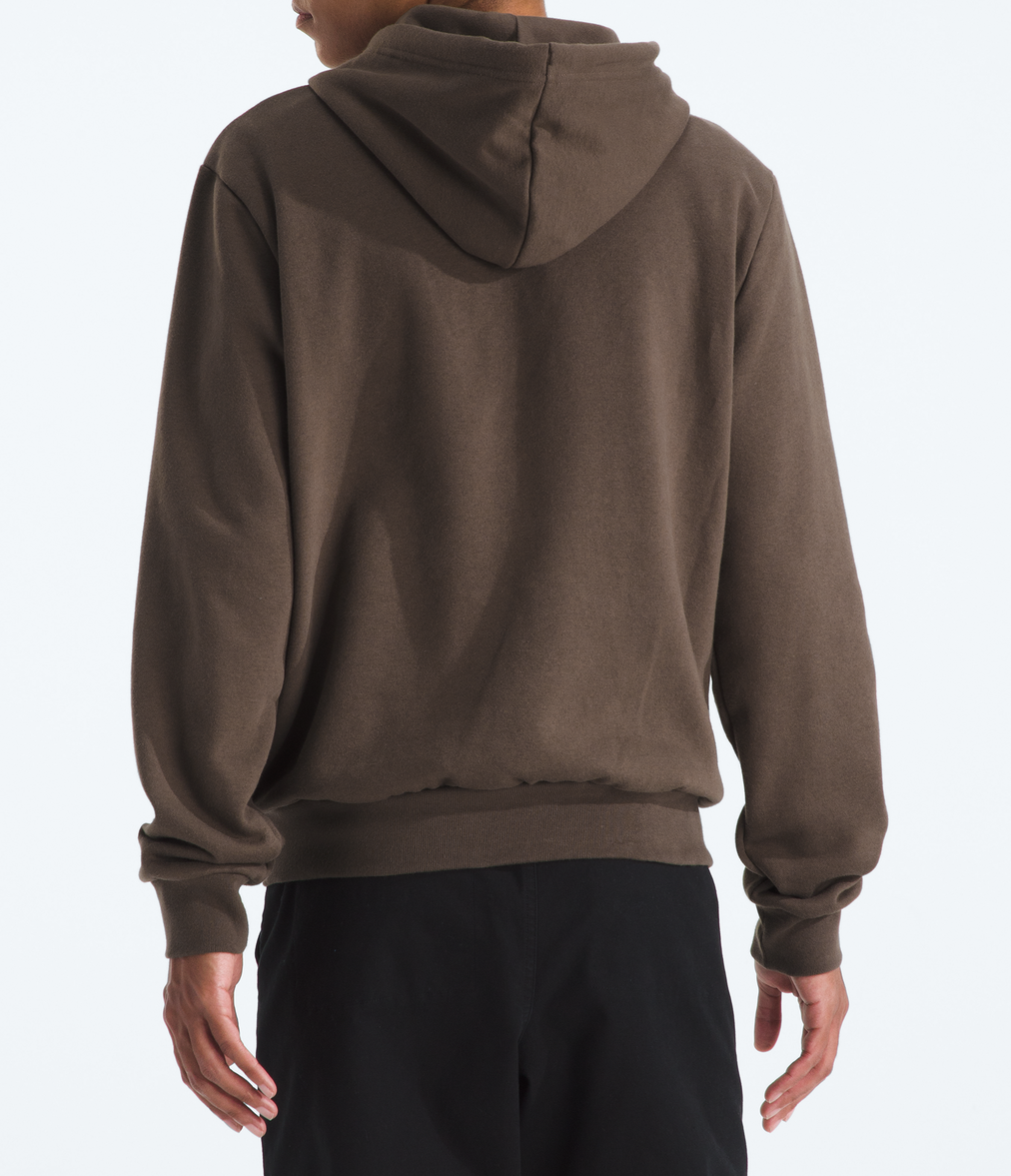 Person wearing a brown hoodie and black pants on a white background