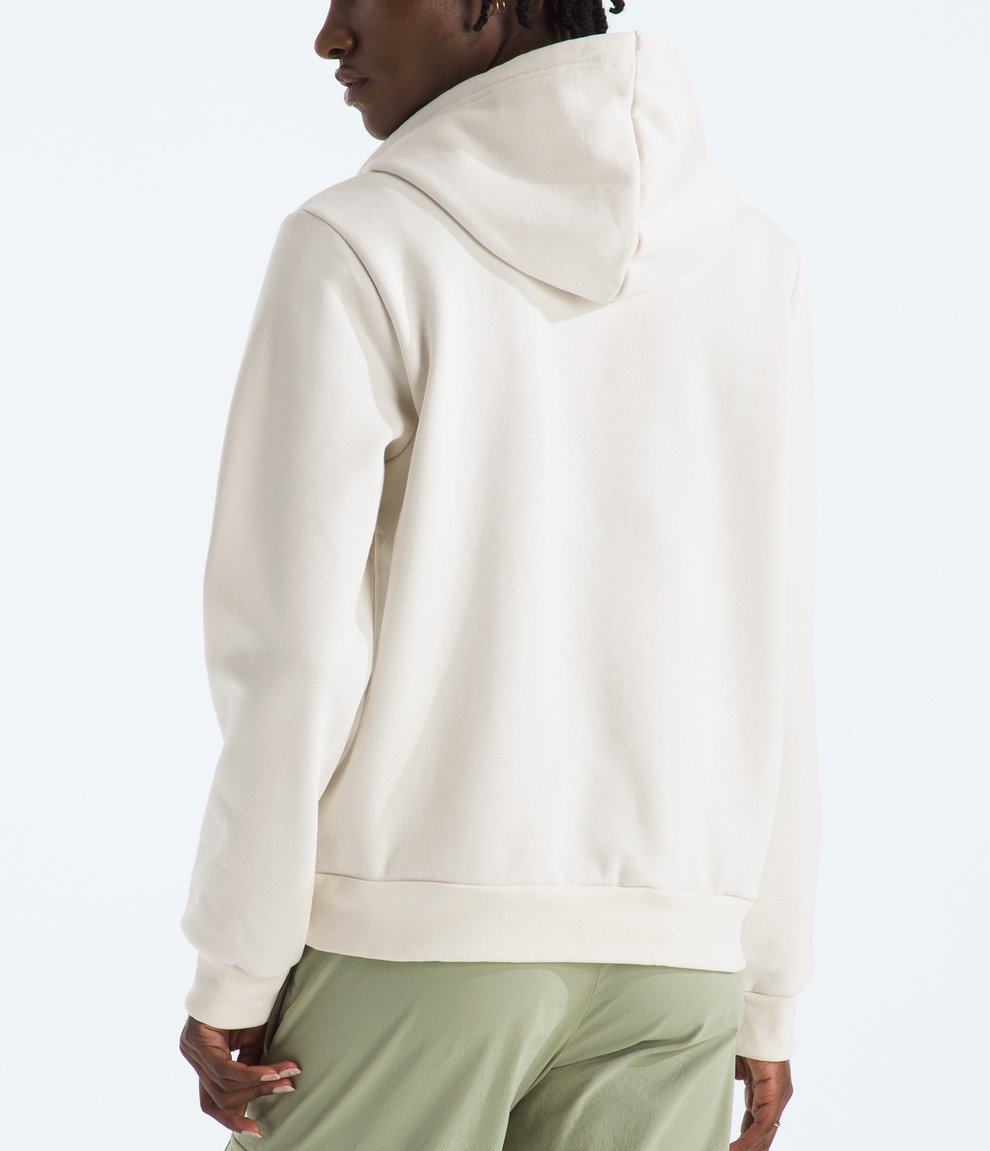 Person wearing a beige hoodie and green pants on a white background