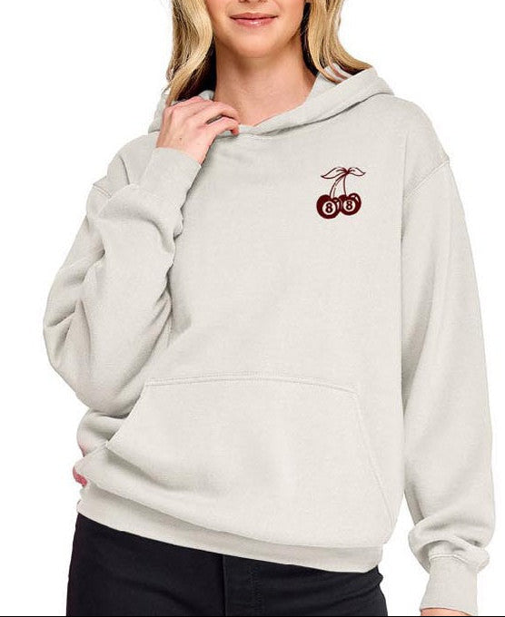 Woman wearing a light gray hoodie with a logo on a white background