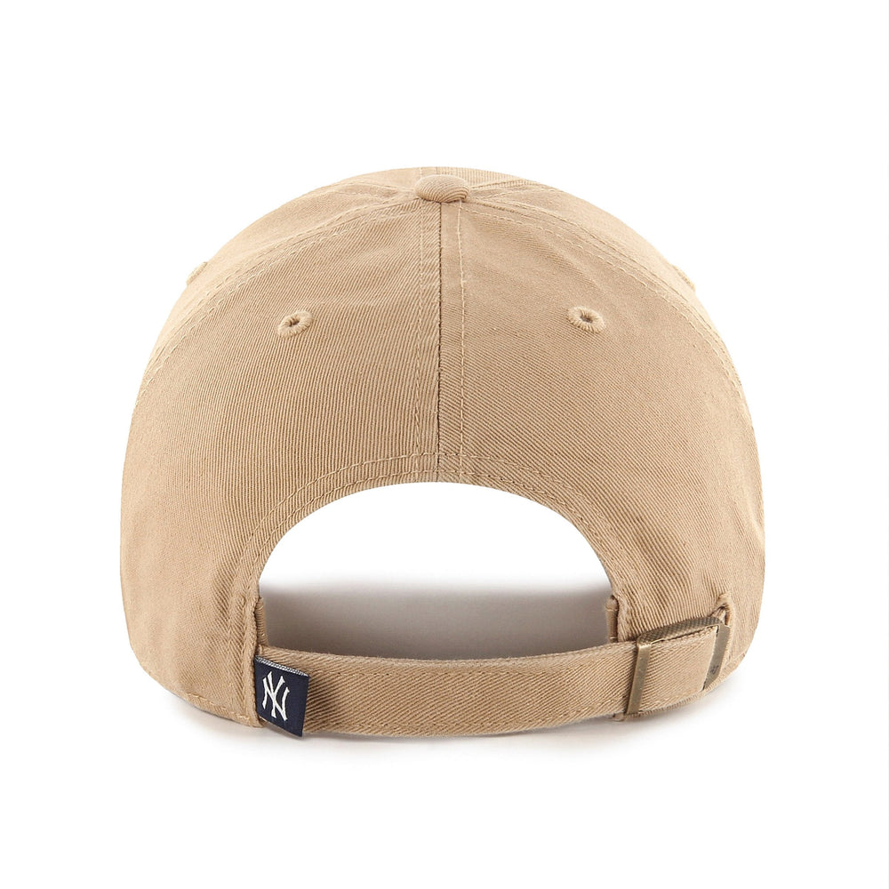 A front view of a beige baseball cap with a prominent navy blue "NY" logo embroidered on the front, and a small "47" logo on the side.