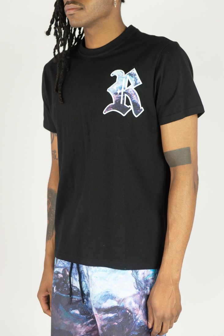 Person wearing a black t-shirt with a logo on a plain background