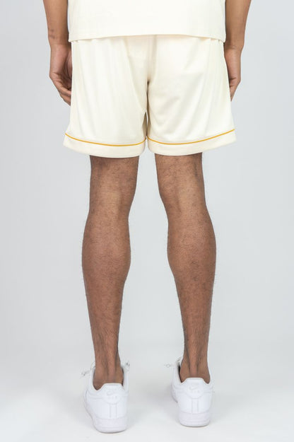 Person wearing white shorts with yellow trim and white shoes on a plain background