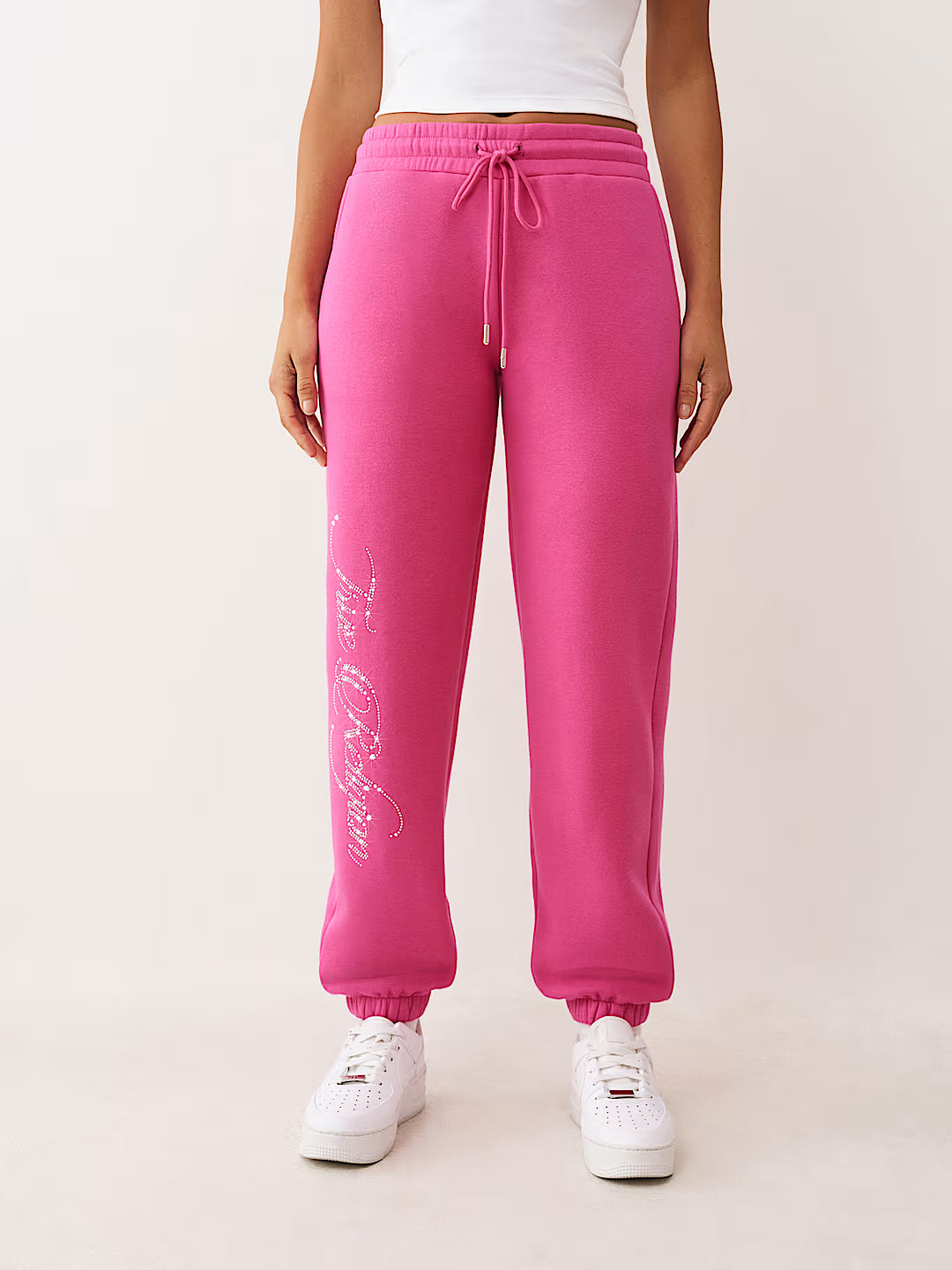 Person wearing pink sweatpants with white text on a light background