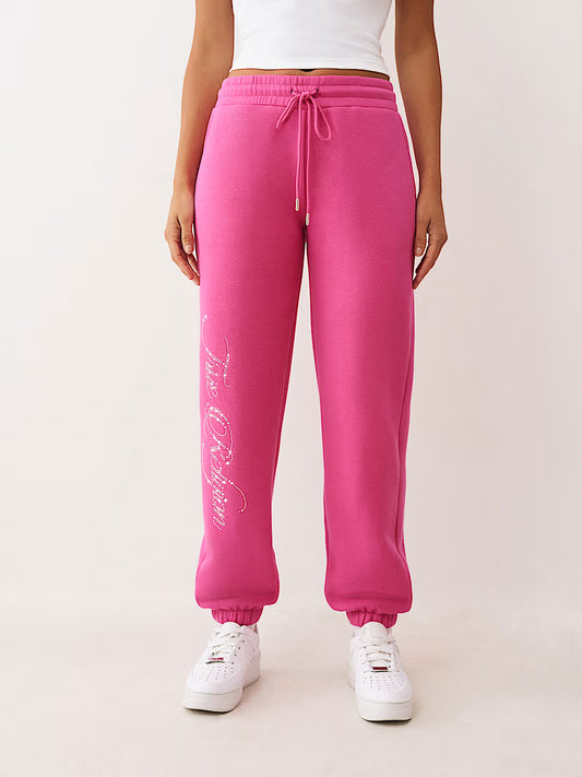 Person wearing pink sweatpants with white text on a light background