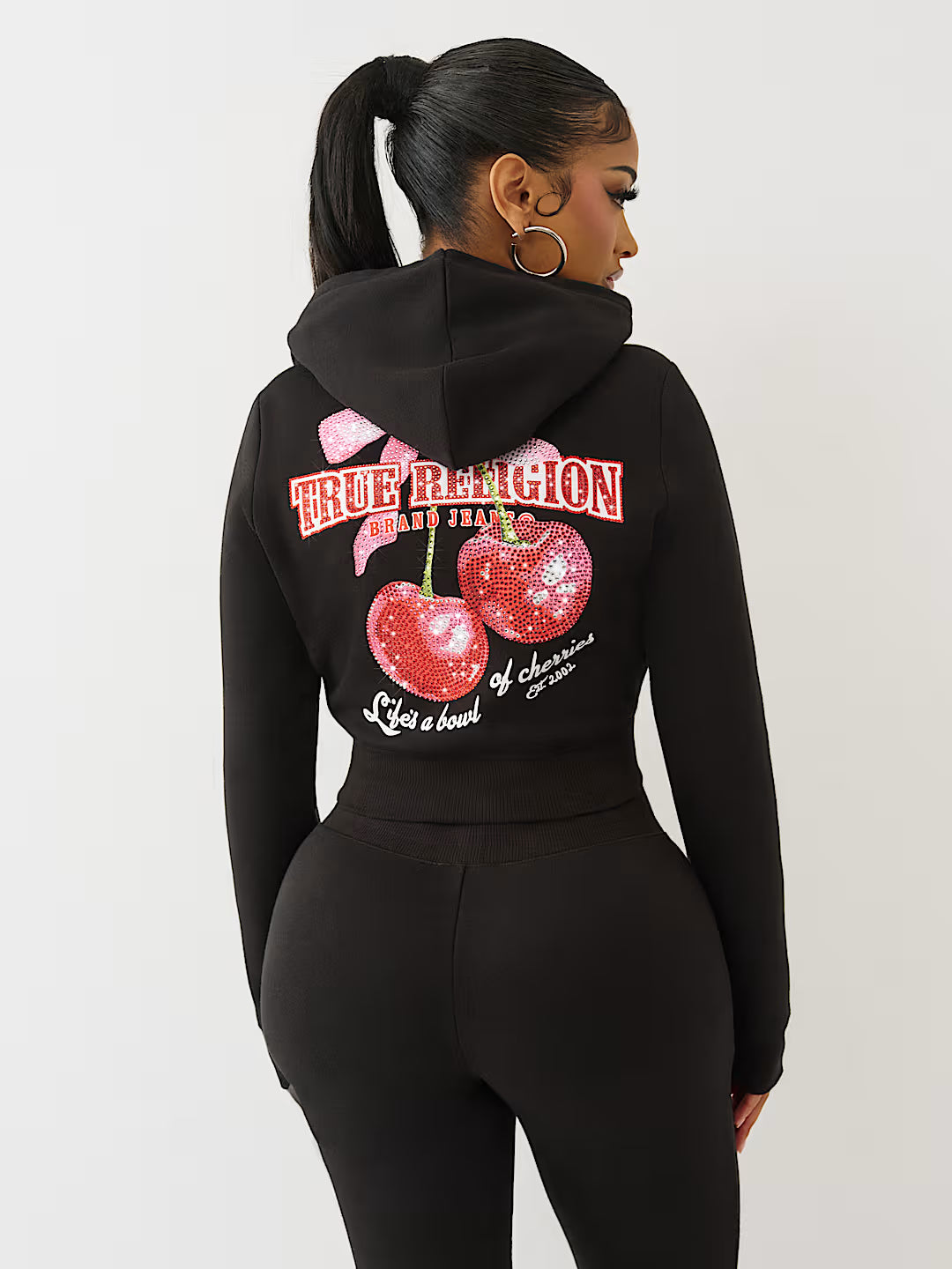 Person wearing a black hoodie with cherry design and text on the back against a white background