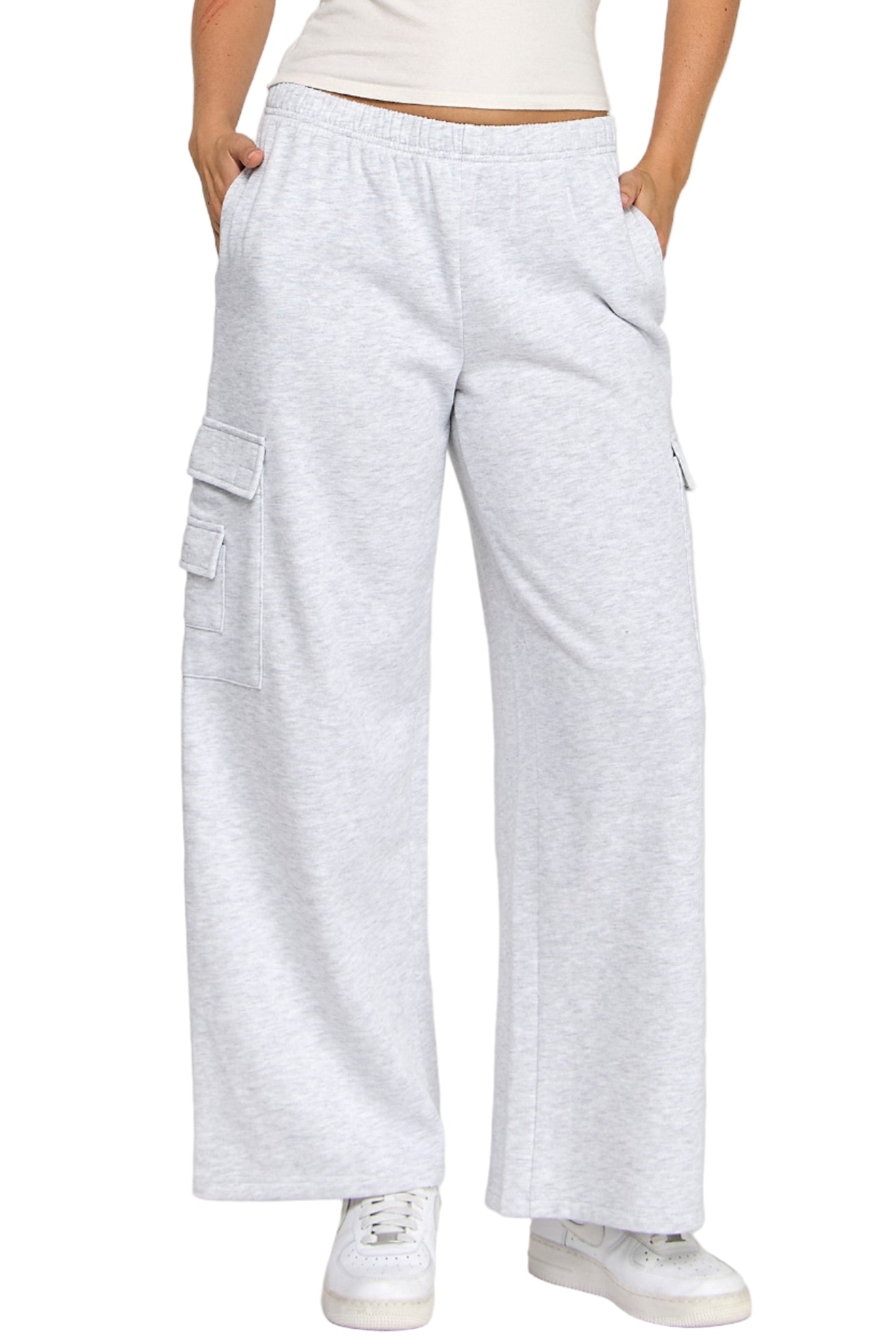 Woman wearing a white tank top and light gray cargo pants on a white background