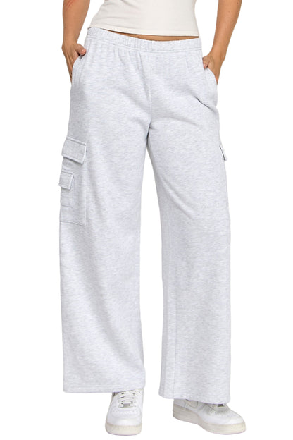 Woman wearing a white tank top and light gray cargo pants on a white background