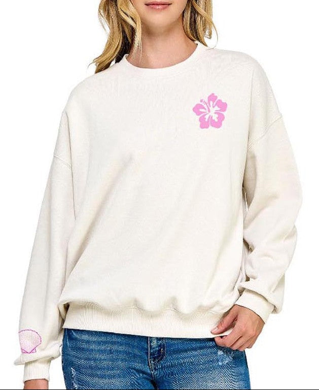 Woman wearing a cream sweatshirt with a pink flower design on a white background 