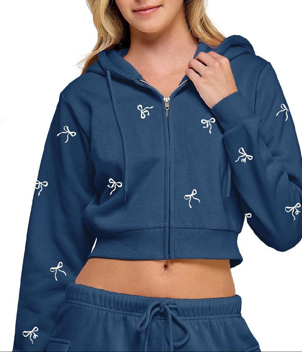 Woman wearing a blue hoodie with white bow designs on a white background