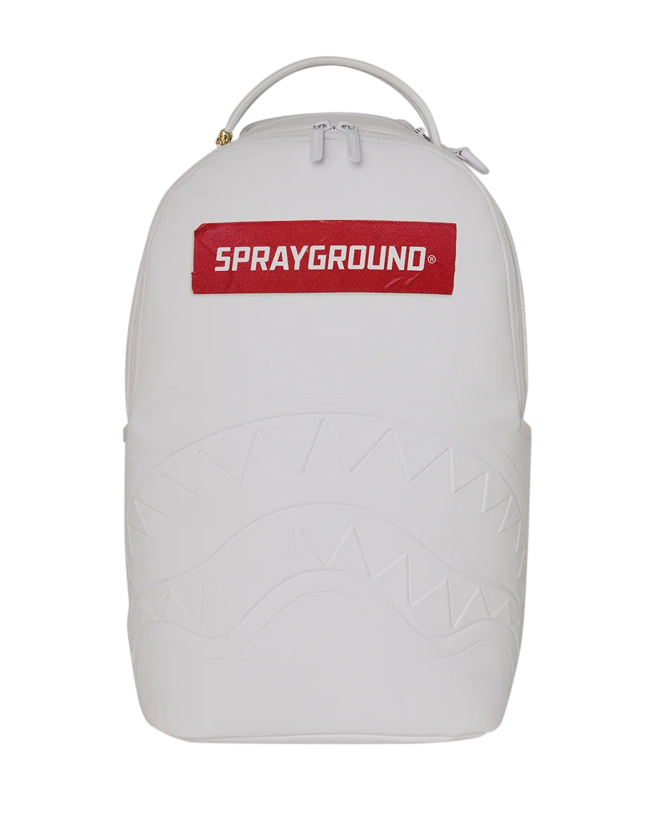 A white Sprayground backpack featuring a red rectangular logo patch on the front with white text, a top carry handle, and an embossed shark-face pattern on the lower half, shown against a plain white background.
