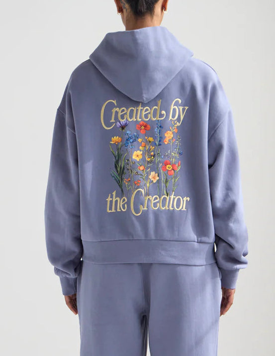 Person wearing a lavender tracksuit with floral text on the back against a white background
