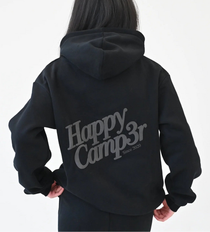 Person wearing a black hoodie with 'Happy Camp3r' text on the back against a white background