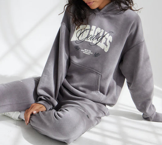 Person wearing a gray hoodie with text sitting on a light background