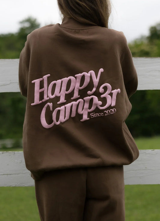 Person wearing a brown sweatshirt with 'Happy Camp3r Since 2020' text outdoors.