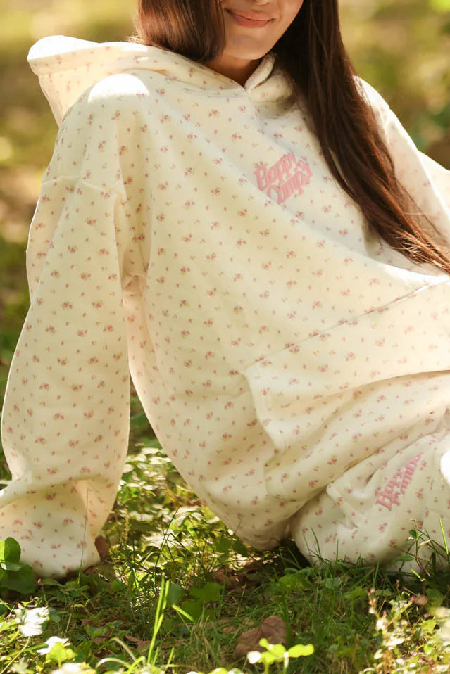 Woman sitting outdoors wrapped in a patterned blanket with a blurred natural background