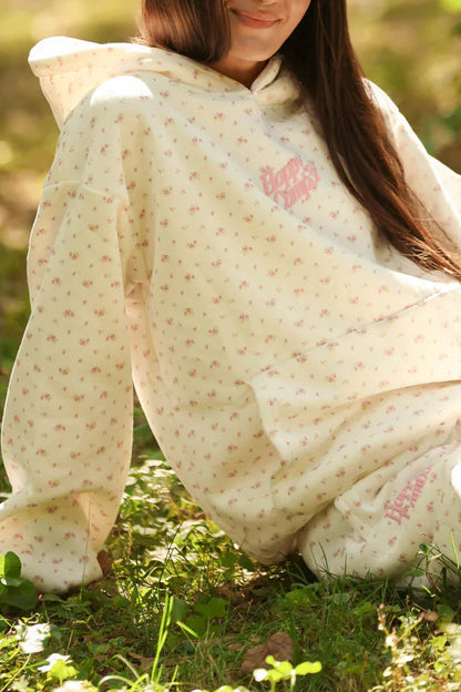 Woman sitting outdoors wrapped in a patterned blanket with a blurred natural background