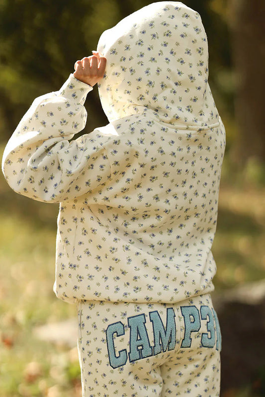 Person wearing a patterned hoodie and pants with 'CAMP' text outdoors.