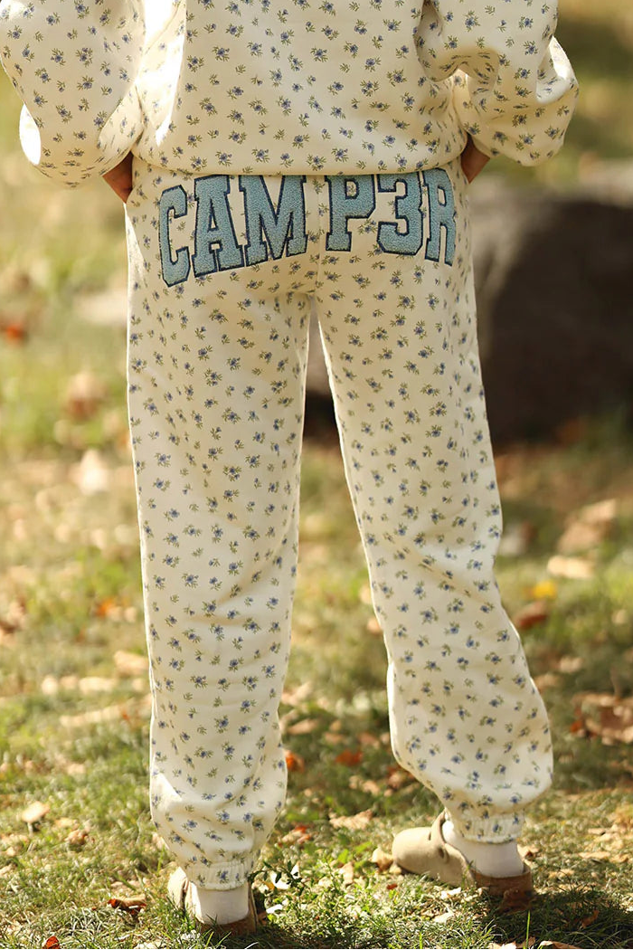 Person wearing a patterned hoodie and 'CAMP 3' pants in an outdoor setting
