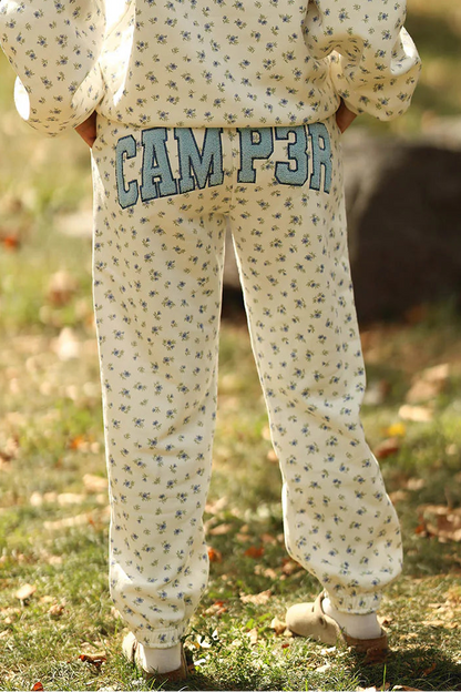 Person wearing a patterned hoodie and 'CAMP 3' pants in an outdoor setting