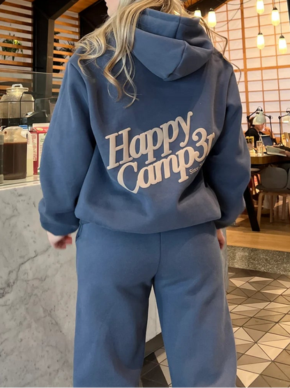Person wearing a blue hoodie with 'Happy Camp31' text in an indoor setting.