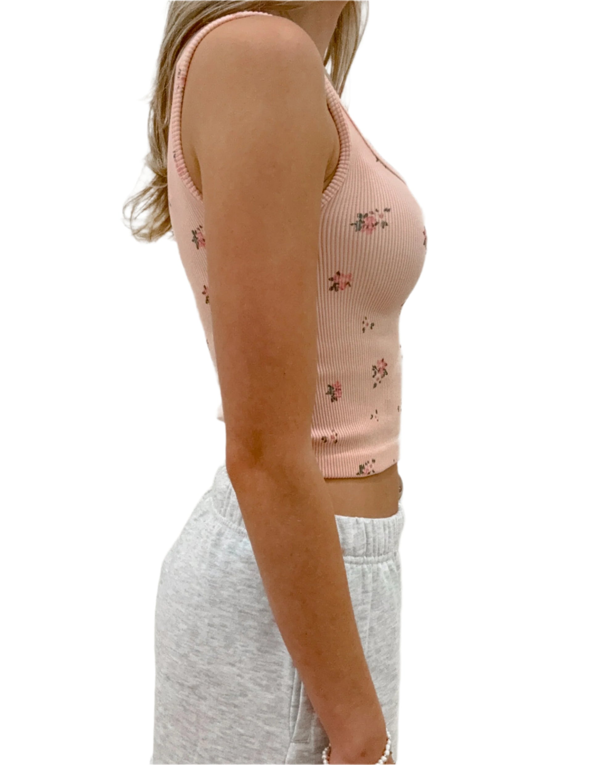 Person wearing a pink floral tank top and gray sweatpants against a white background