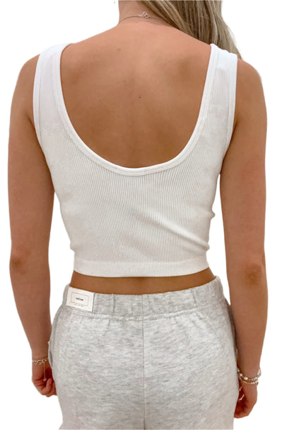 Person wearing a white tank top and gray pants with a blurred background