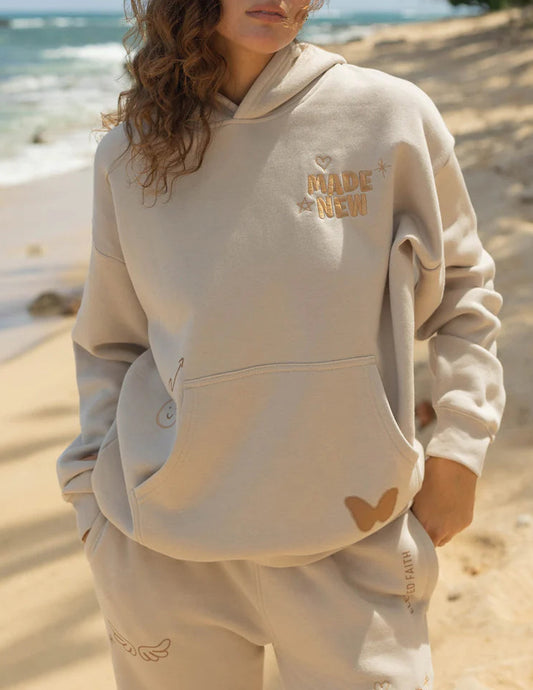 Person wearing a beige hoodie and pants on a beach 