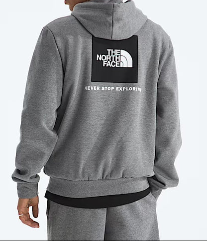 Person wearing a gray hoodie with The North Face logo on the back against a light gray background. 